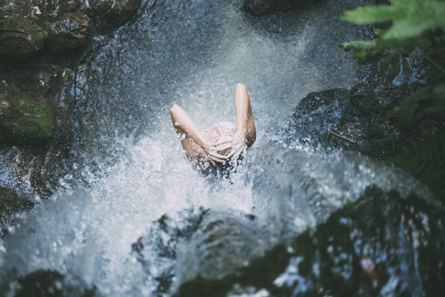 Woman rinsing in a waterfall